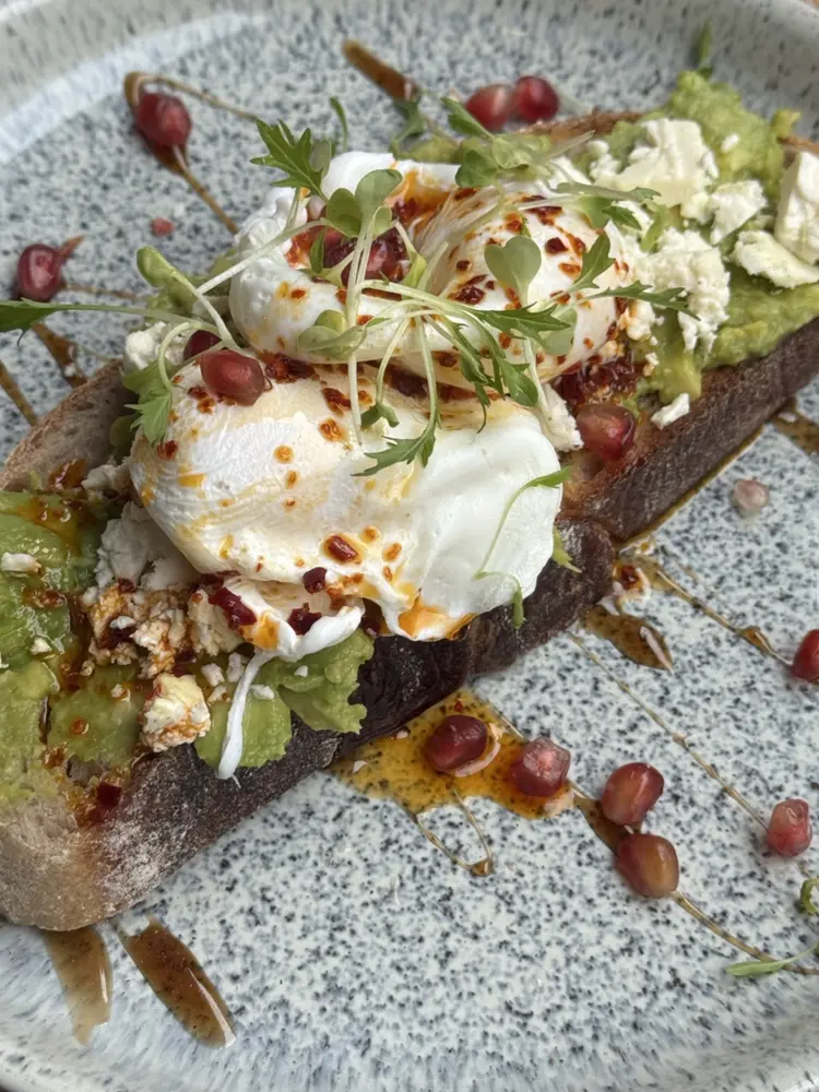 Poached eggs with chilli butter, feta and pomegranate on sourdough